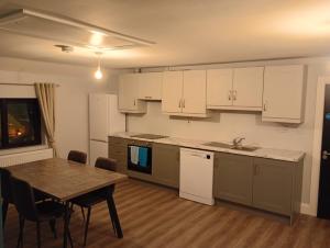 a kitchen with white cabinets and a table and a table and chairs at Adies Bar & Restaurant in Lanesborough