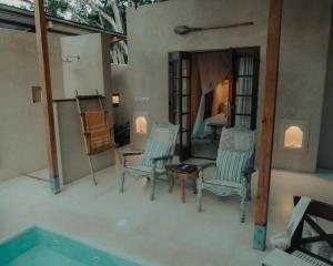 a room with three chairs and a swimming pool at Monkey Suites in Diani Beach