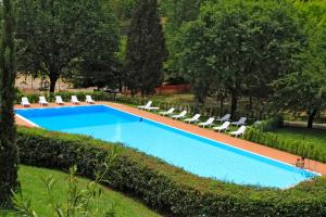 a swimming pool in a garden with chairs and trees at Camping Siena Colleverde in Siena