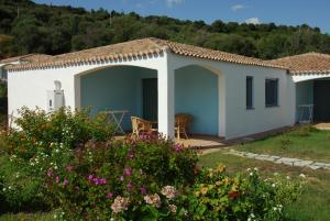 a small white house with a garden and flowers at Hotel Baia Cea in Bari Sardo