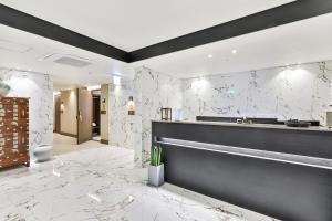 a bathroom with white marble walls and a sink at Hotel Onggi in Gyeongju
