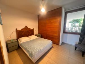 une chambre avec un lit avec une tête de lit en bois et une fenêtre dans l'établissement appartement Calvi, à Calvi