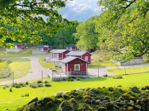 a group of red cabins in a green field at Stuga - Ulvereds Hjorthägn in Laholm