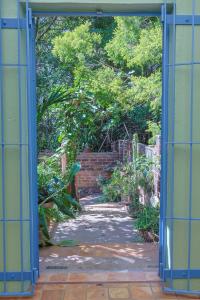 eine offene Tür zu einem Garten mit einem Weg in der Unterkunft Forest Haven in Harare + 2 Fotos