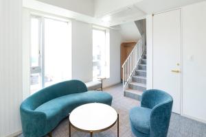 Una sala de estar con dos sillas azules y una mesa. en Hotel Comento Yokohama Kannai, en Yokohama