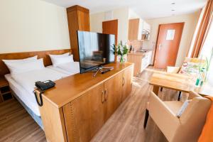 a room with a bed and a desk with a television at Hotel Atlantic Juist in Juist