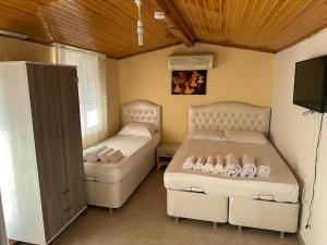 two beds in a room with a tv and a bedskirts at Casa Luma Avşa Island in Avşa Adası