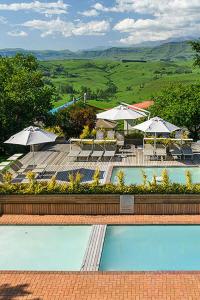 - une vue sur la piscine avec des parasols et des chaises dans l'établissement Caley mountain resort, à Memel