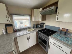 a small kitchen with a stove and a sink at Sea Shanty in Newquay +4 photos