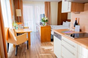 a kitchen with a table and a room with a bed at Hotel Atlantic Juist in Juist