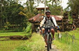 a man riding a bike down a dirt road at Downhill Cycling Ubud with Volcano, Jungle, Rice Terrace with meals in Tampaksiring