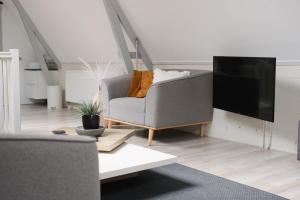 a living room with a gray couch and a flat screen tv at Appartement Dokkum in Dokkum