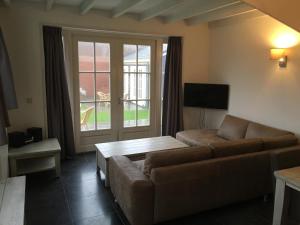a living room with a couch and a large window at Kerkplein Vakanties in Vrouwenpolder