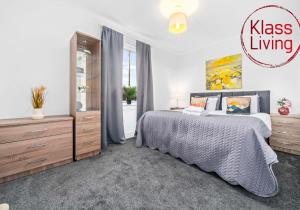 a bedroom with a king sized bed and a dresser at Broomfield Apartment by Klass Living Airdrie in Airdrie