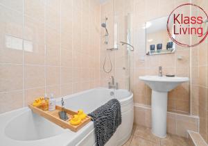 a bathroom with a tub and a sink and a toilet at Coats Street Apartment by Klass Living Coatbridge in Coatbridge +26 photos