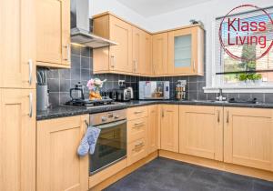 a kitchen with wooden cabinets and black counter tops at Coats Street Apartment by Klass Living Coatbridge in Coatbridge