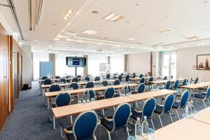 a room with tables and chairs and a projection screen at Dorint Charlottenhof Halle (Saale) in Halle an der Saale