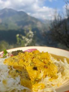 a plate of food with rice and curry at Baserah - Cafe & Stay in Jibhi +37 photos