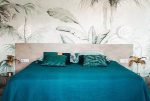 a bedroom with a blue bed with plants on the wall at La Villa Nais PADEL&PISCINE -Suites & Appartements in Bormes-les-Mimosas