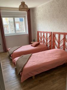 two beds in a bedroom with a window at Les Herbes Maritimes Gîte in Hirel