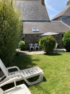 a group of lawn chairs and a bench in a yard at Les Herbes Maritimes Gîte in Hirel