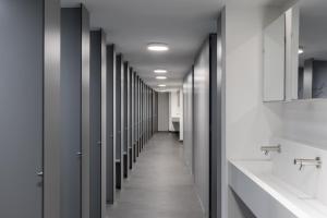 a row of stalls in a bathroom with sinks and mirrors at Zedwell Capsule Hotel Piccadilly Circus in London +10 photos