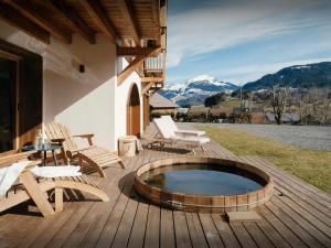 a deck with a hot tub and chairs and mountains at La Ferme de Mila - OVO Network in Saint-Jean-de-Sixt