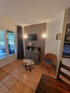 a living room with a tv and a chair and a table at Chez Anne WIFI dans le logement in Argentat