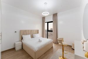 Un dormitorio blanco con una cama y una silla. en Stunning 2 Bed in Cyan Beach Residence, en Sharjah