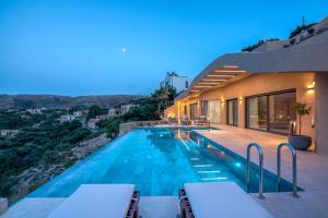 a swimming pool with chairs next to a building at Villa Tierra in Kissamos