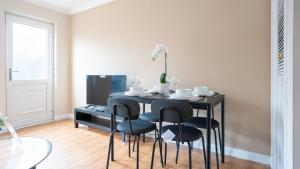 mesa de comedor negra con sillas y TV en Forbes House, en Glasgow