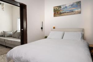 a bedroom with a white bed and a couch at נוף לפרדסים תל מונד - דירה מהממת עם 2 חדרי שינה ומרפסת גג in Kefar Ziw