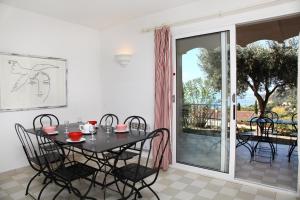a dining room with a table and chairs and a sliding glass door at Residenza l 'Alivetu in Cargèse
