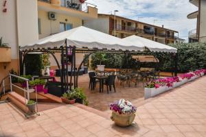 eine Terrasse mit einem weißen Sonnenschirm sowie Tischen und Stühlen in der Unterkunft Hotel La Villa in Corigliano Calabro