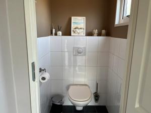 a bathroom with a white toilet in a room at Sfeervol chalet op familiepark in Oostkapelle vlakbij strand in Oostkapelle +17 photos