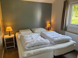 two white beds in a bedroom with two lamps at Sfeervol chalet op familiepark in Oostkapelle vlakbij strand in Oostkapelle