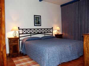 a bedroom with a bed with a blue bedspread and two lamps at Agriturismo Fattoria Il Casalone in Orbetello