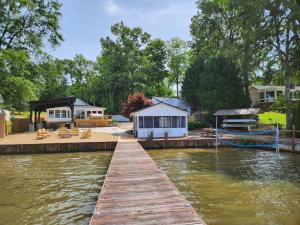 a dock with a house and a boat on the water at Lake Greenwood Lodge Main House and guesthouse in Isle of Pines