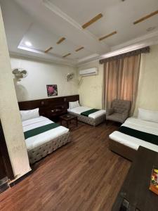 Tahkāl PāyānHotel Crescent的有两张床和一把椅子的酒店房间