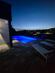 a swimming pool at night with blue lights at Apartmani City ES in Cazin