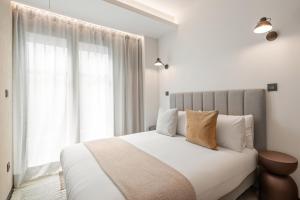 a bedroom with a bed with white sheets and a window at Dobo Madrid Moncayo in Madrid