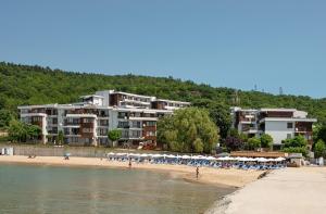 a beach with chairs and umbrellas in front of a building at Messambria Beach Apartments in Sveti Vlas