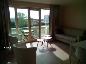 a living room with a couch and tables and a balcony at Apartment Green Garden Block L in Middelkerke