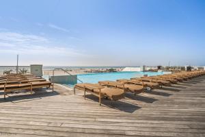 a row of benches on a boardwalk next to a swimming pool at Residence 1201 At The Grand in Wildwood