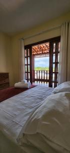 a large bed in a room with a large window at Linda casa com excelente localização em Boipeba in Ilha de Boipeba