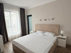 a bedroom with a large bed with a sign on the wall at Margelelor Cozy Apartments in Bragadiru +38 photos