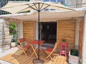 a table and chairs on a wooden deck with an umbrella at Chambre spacieuse vue sur le Ventoux in Buis-les-Baronnies