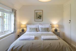 une chambre avec un grand lit blanc avec deux lampes dans l'établissement Danny Lodge - Country Cottage Near Brighton by Huluki Sussex Stays, à Hurstpierpoint