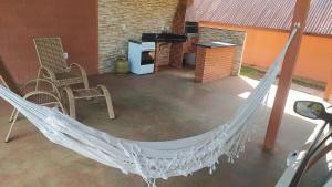 a hammock in a patio with chairs and a stove at Aconchego da Montanha - chalé in Marechal Floriano