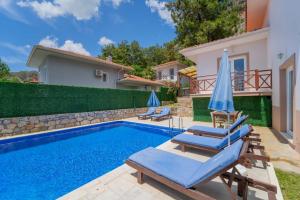 una piscina con 2 sillas de césped y sombrillas en Villa TURUNÇ - Göcek, en Fethiye
